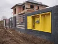 Żółta skrzynka z przyłączem gazowym na tle budowy domu. Widoczny fragment instalacji gazowej, regulator ciśnienia. Przyłącze gazowe krok po kroku.