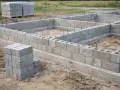 Budowa fundamentów z pustaków betonowych. Widać ułożone bloczki i zbrojenie. Jaki beton na fundament? Ten wygląda solidnie.