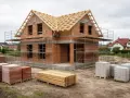 Budowa domu 120m2. Cegły, drewno i rusztowania czekają na dalsze prace. Zastanawiasz się, ile kosztują fundamenty pod dom 120m2?