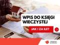 Wpis do księgi wieczystej po spadku. Dłonie trzymają model domu, obok dokumenty i kalkulator.