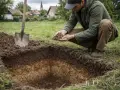 Mężczyzna bada gleby pochodzenia mineralnego, trzymając grudkę ziemi w dłoniach. Obok stoi łopata.