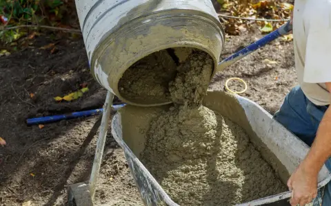 Betoniarka wylewa świeży beton do taczki. Oto jak zrobić beton w wiadrze, gdy potrzebujesz go do małych prac.