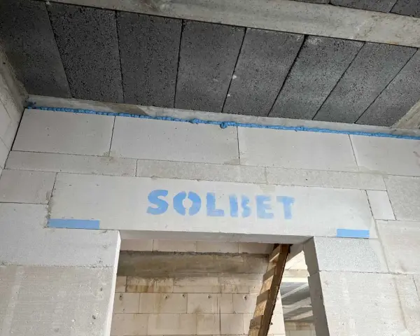Dylatacja co to? Widoczna szczelina wypełniona pianką między betonem a bloczkami z napisem SOLBET.