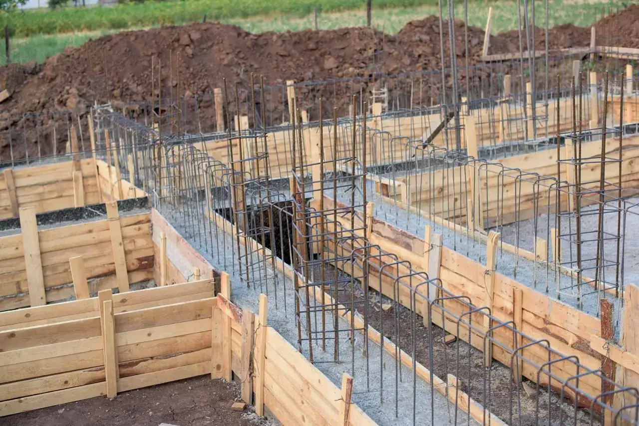 Drewniany szalunek fundamentowy z zbrojeniem stalowym, gotowy do zalania betonem.