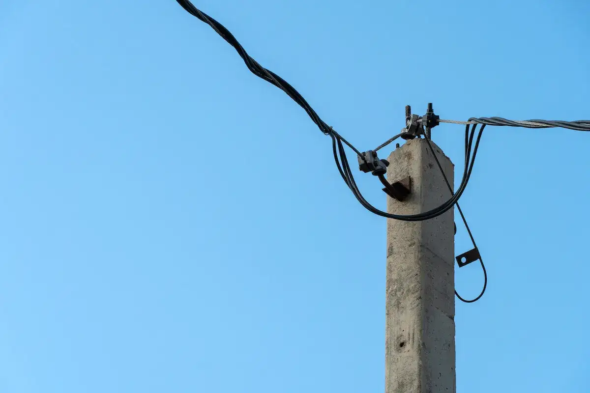 Betonowe słupy energetyczne z kablami na tle błękitnego nieba.