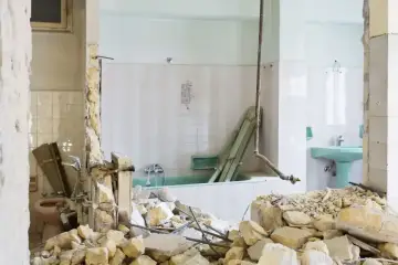 Ruiny łazienki po remoncie. Zniszczone ściany, gruz i wanna. Kara za mieszkanie w nieodebranym domu.